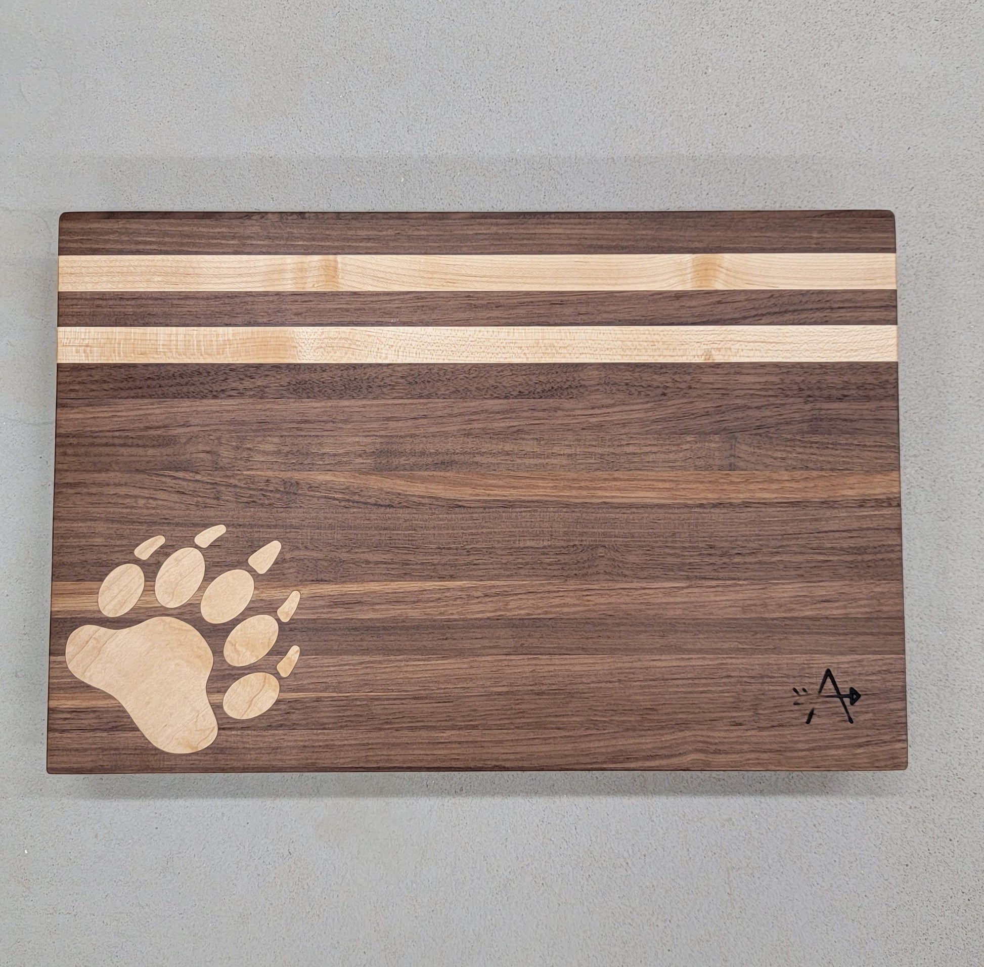 " Bear " Walnut and Maple Wood Cutting Board

Artist: Kevin Shimkus

Edge-grain cutting board made of walnut and maple

Bear print inlay in lower left corner

Two maple stripes at the top of board

Four small feet on bottom side of cutting board to prevent slipping

WoW your guests at your next get together with this hardwood serving board

12" wide by 18" long by 2" deep

8.5 lbs