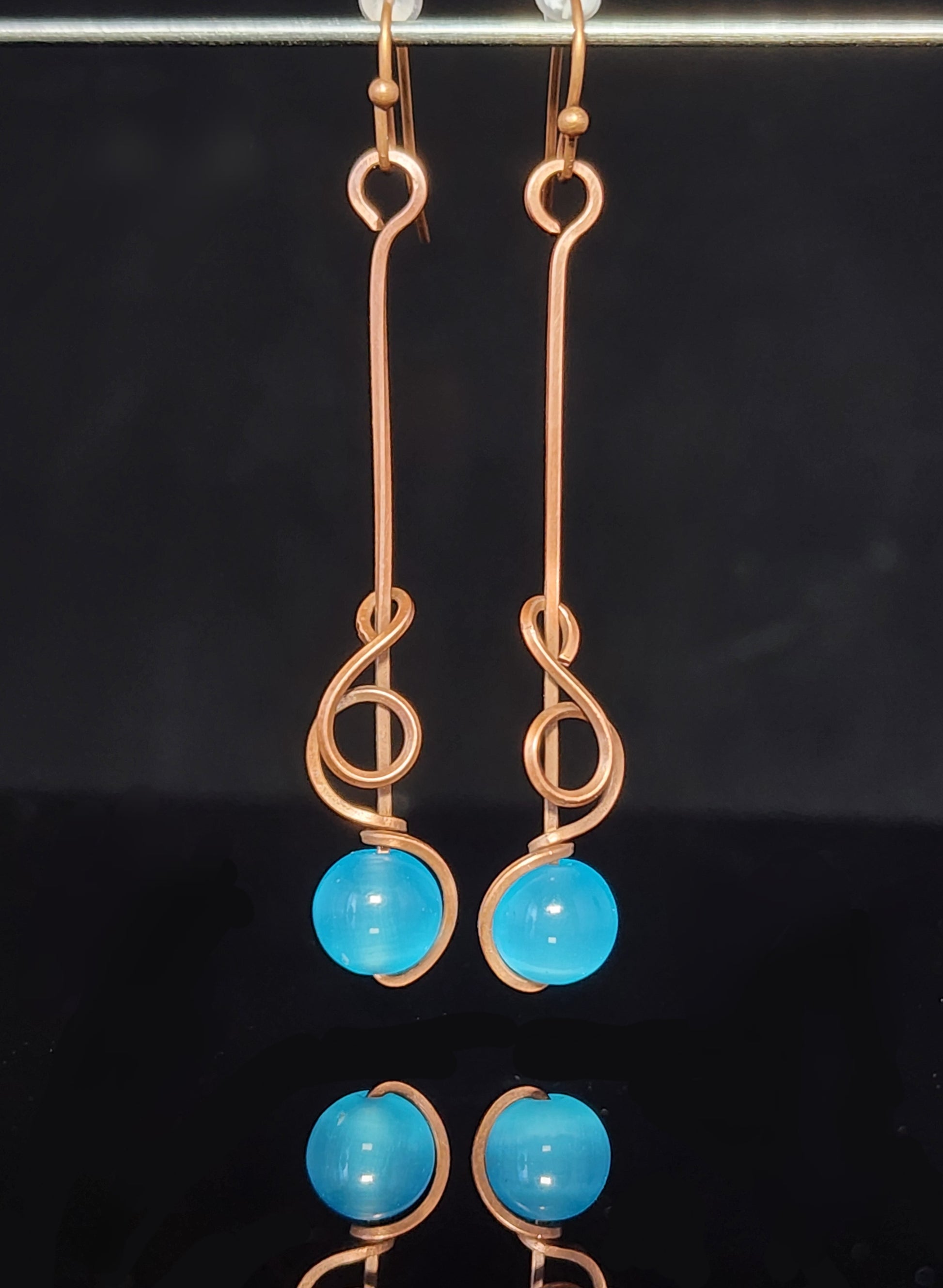 Blue Cat's Eye Sphere Dangle Earring Artist: Lindsey Griffin  Brilliant Blue cat's eye sphere wrapped in copper wire   2" long x 1/4" wide&nbsp;   Copper wires earring hooks   Beautiful dangle earrings   Cleaning instructions and cloth are included