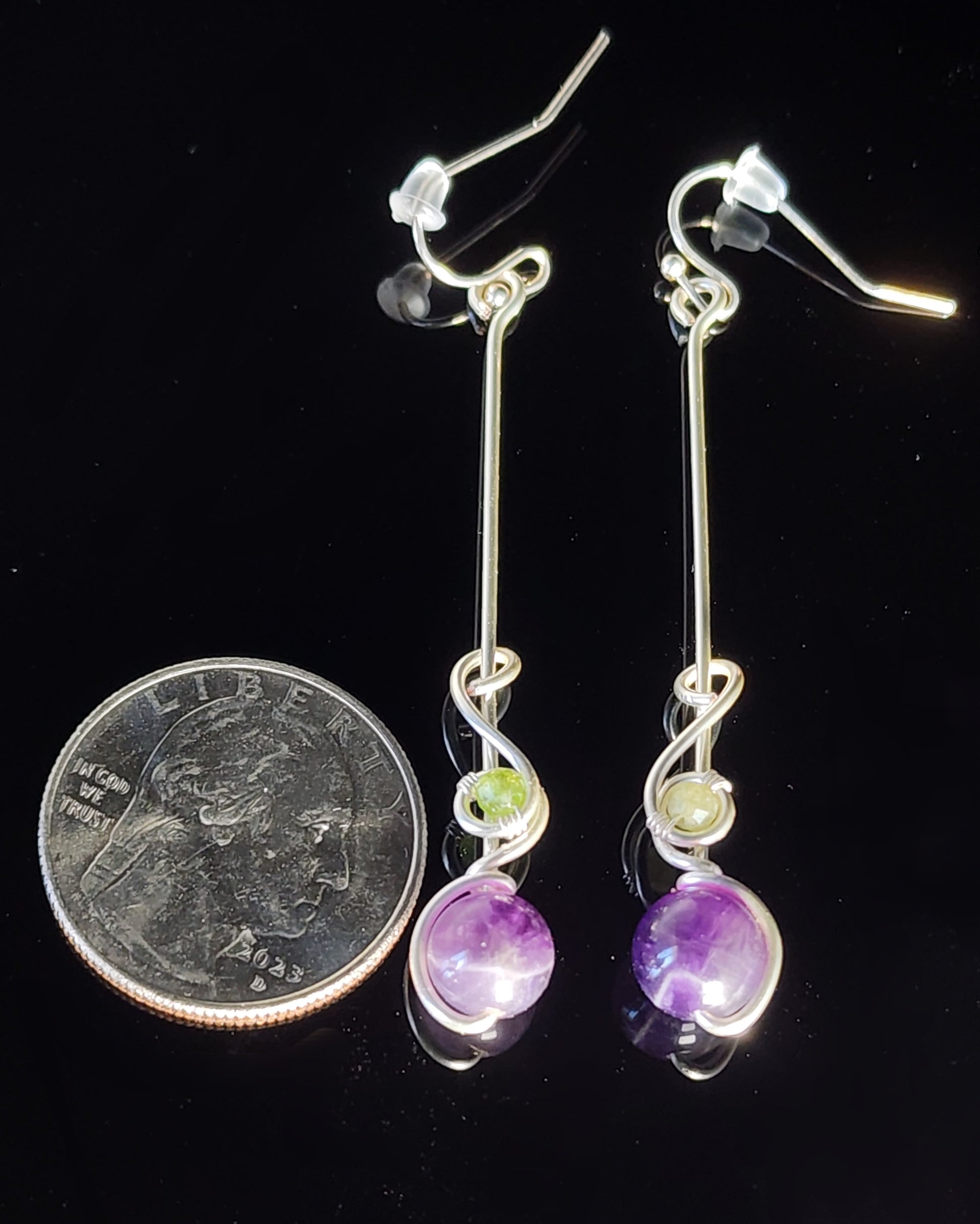 methyst Sphere and Tourmaline Bead Dangle Earrings Artist: Lindsey Griffin  Sometimes a little color is all you need.  Amethyst sphere wrapped in silver colored artistic wire with green tourmaline bead&nbsp;   Simple design. Strong statement  2" long x 1/4" wide&nbsp;   Stirling silver wires   Beautiful dangle earrings   Cleaning instructions and cloth are included