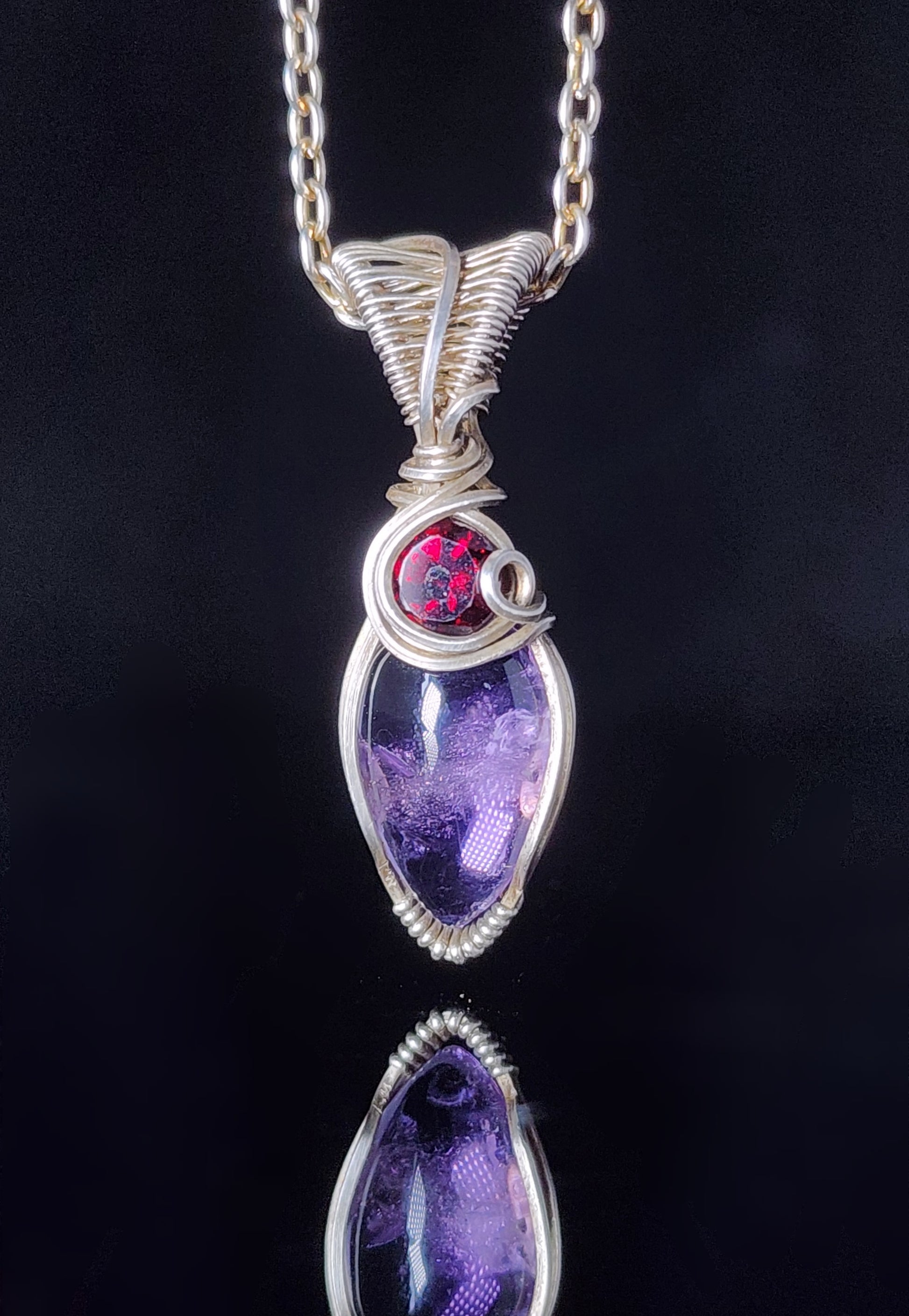 Amethyst and Garnet Wire Wrapped Pendant  Artist: Lindsey Griffin&nbsp;   Amethyst and&nbsp; faceted garnet in wrapped&nbsp; sterling silver wire   16" silver plated snake chain