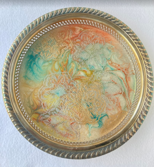 round stainless steel serving tray. in the bottom of the tray iare flowers hand painted with acrylic and covered witha clear poly resin