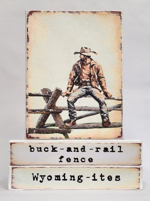 " Buck and Rail Fence Wyoming-ites" Canvas Print Artist: Catherine Holt  Print on canvas with wooden framework   Copy from artists original  Cowboy in jeans and leather jacket sitting on a buck rail fence  Buck and Rail Fence label on one side and Wyoming-ites label on the other  If you have lived in Wyoming, you may have helped build a buck fence, or sat on one.