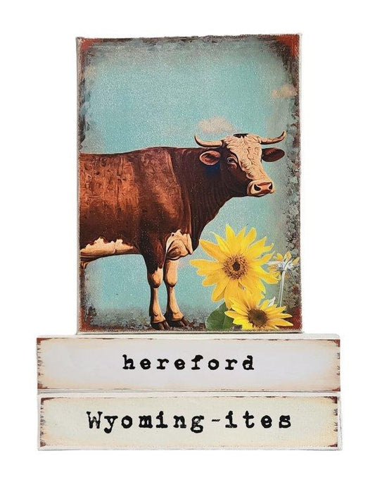 " Hereford Wyoming-ites" Canvas Print Artist: Catherine Holt  Print on canvas with wooden framework   Copy from artists original artwork   Hereford cow with sunflowers   Hereford label on one side and Wyoming-ites label on the other  Wyoming-ites is a series of&nbsp; "life in Wyoming" lifestyles and experiences!