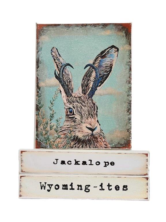 " Jackalope Wyoming-ites" Canvas Print Artist: Catherine Holt  Print on canvas with wooden framework   Copy from artists original  Jackalope on a blue green background  The rare jackalope is very elusive and rarely seen.  Jackalope label underneath the painting and Wyoming-ites label below.  6" long x 8" high x 1 1/2" wide  Signed and numbered by the artist