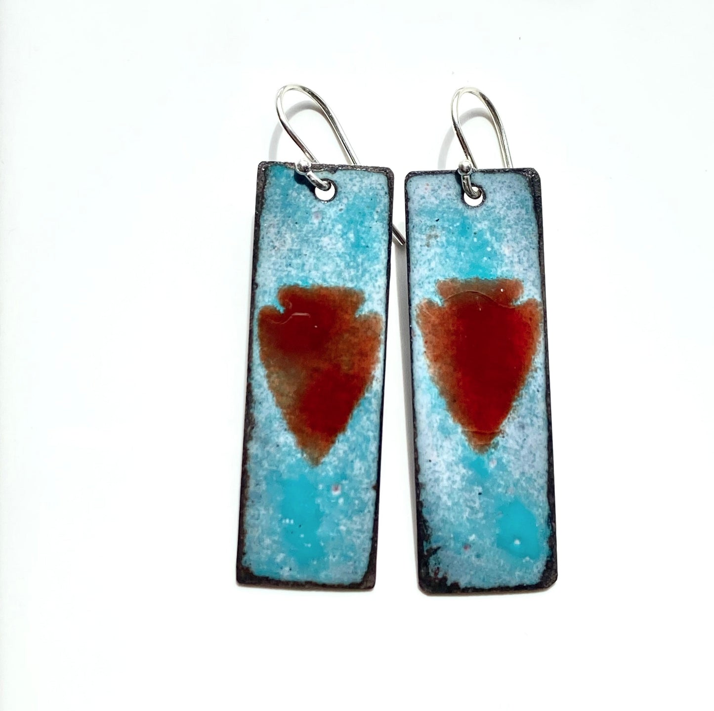 Red Arrowhead On Blue Enamel Earrings Jewelry Artist: Kristie Brown Red Arrowhead on Blue Patina background  Long Rectangle Earrings  1 3/4" long x 1/2" wide  Sterling Silver ear wires